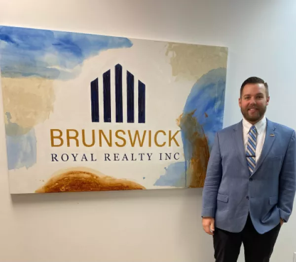 Realtor standing by office sign