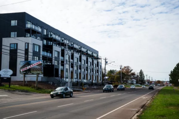 A new apartment building with a "now leasing" sign out front