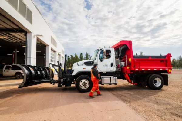 Snowplow with driver standing next to it