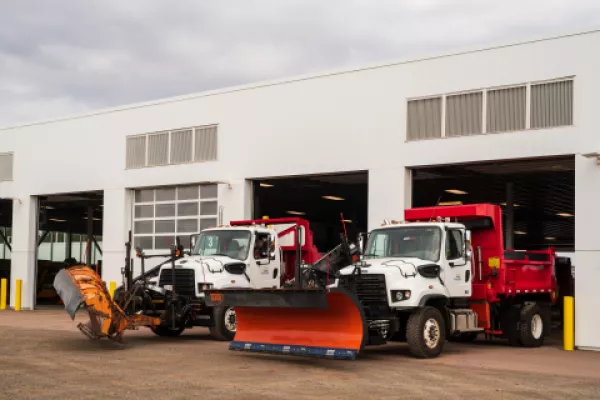 Two snowplows pulling out of garage