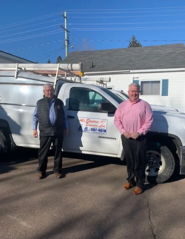 Al and Lee standing in front of one of their work trucks