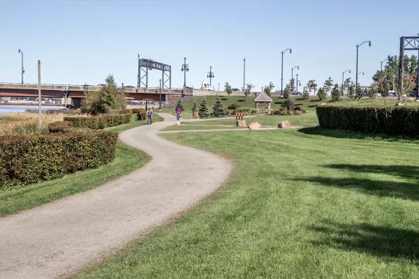 a tidy walking path next to the river with two bikers on it