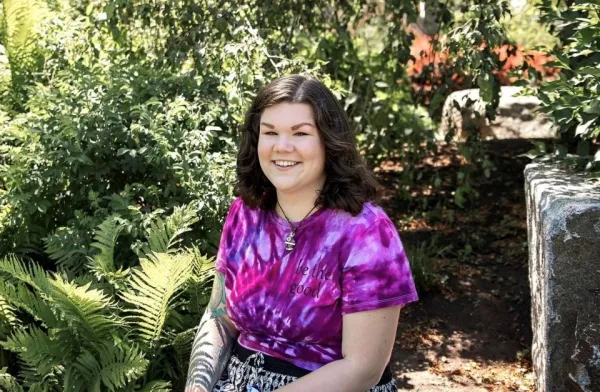 Young woman with brown hair sits in garden