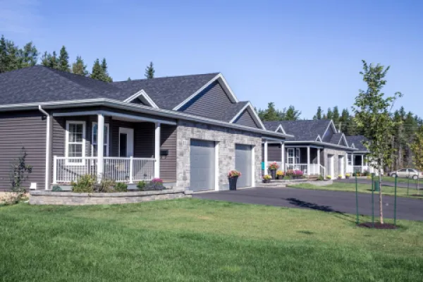 A row of semi-attached housing with green lawn and blue sky