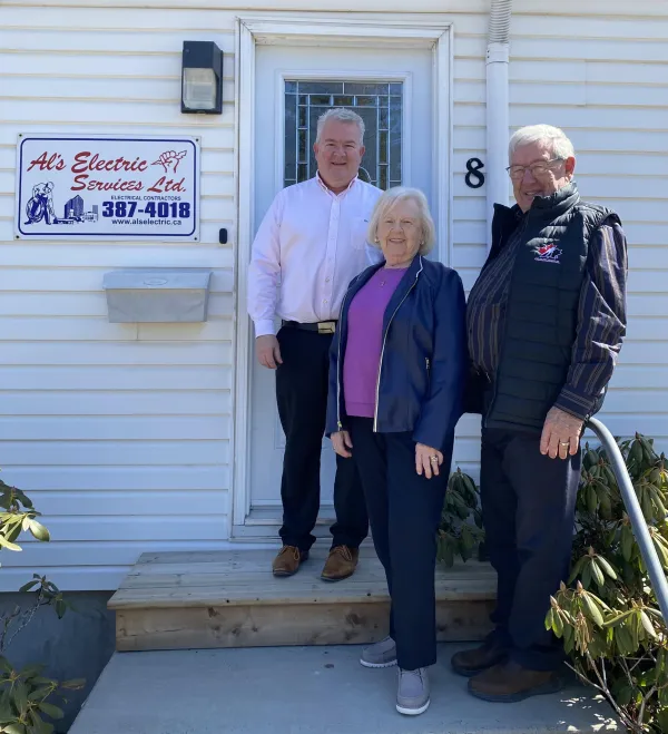 Owners standing beside Al's Electric sign