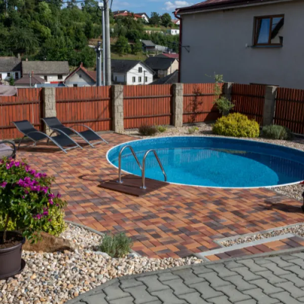 Backyard with a round pool surrounded by a path and plant decor.