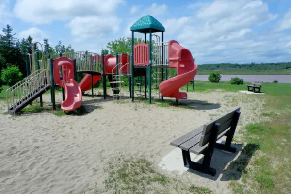 A playground with benches and a blue cloudy sky in the background 