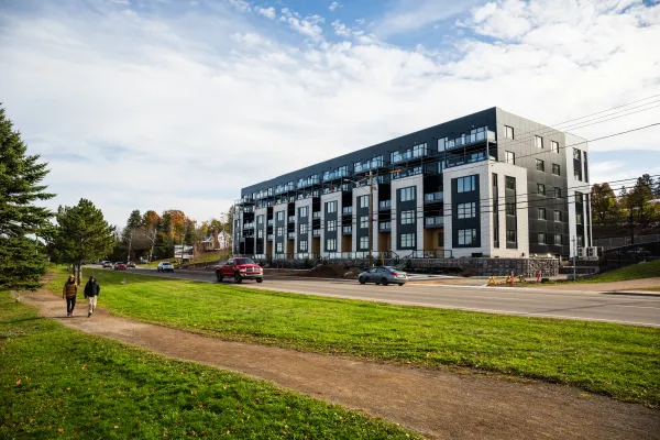 two people walk on riverfront trail with apartment in background