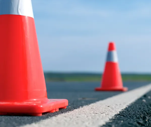 Two orange pylons set along a solid white line on the road