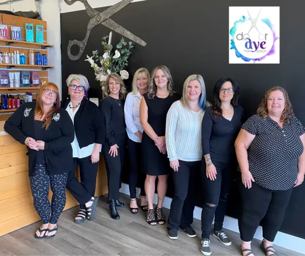 Hair salon staff standing in a line smiling inside their store