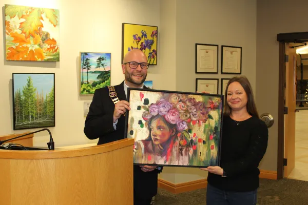 Mayor and guest holding artwork and smiling