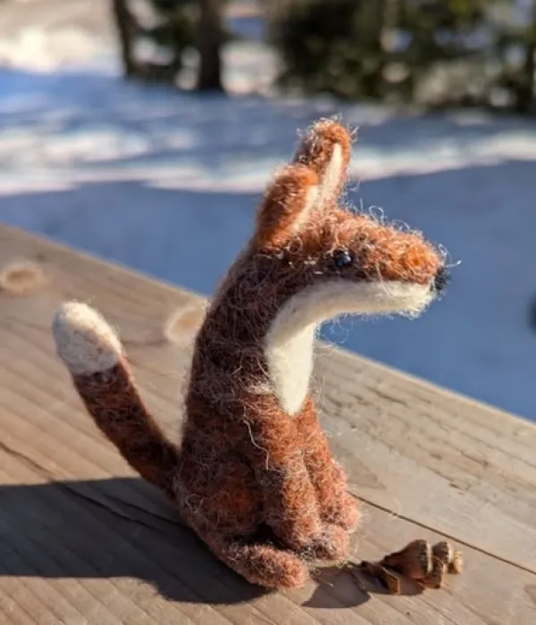 Stuffed felt fox sitting on an outside deck