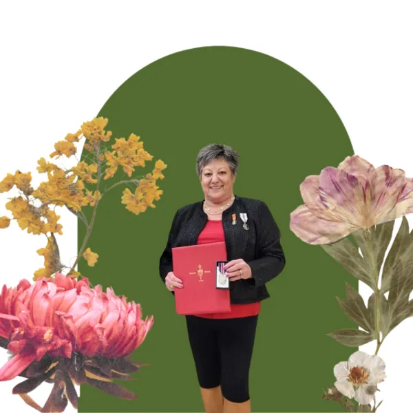 A woman standing and smiling in front of a green floral backdrop